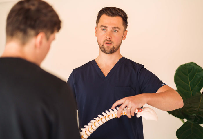 Henry explaining a model of the spine to a patient during an osteopathy consultation